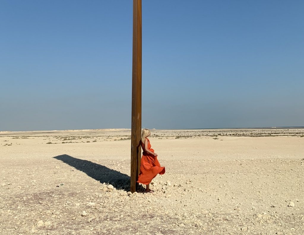 Tijana in burnt orange Kalita dress leaning against East-West/West-East in Qatar.

Kalita dress