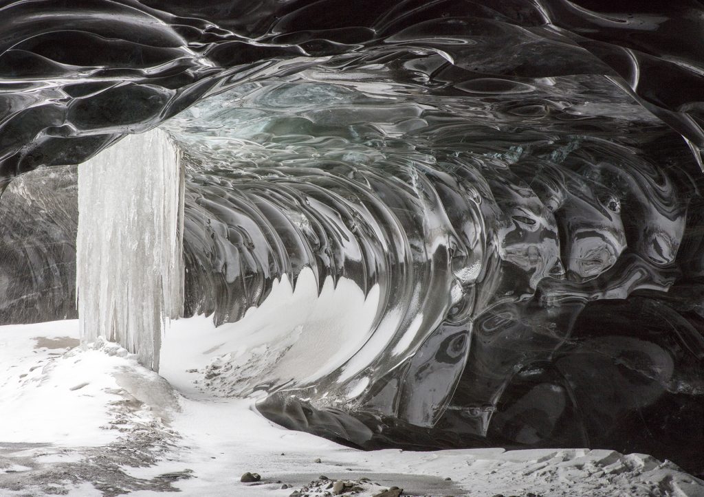 Breathtaking view of frozen waterfalls and walls carved of black ice in the glacier caves in Iceland