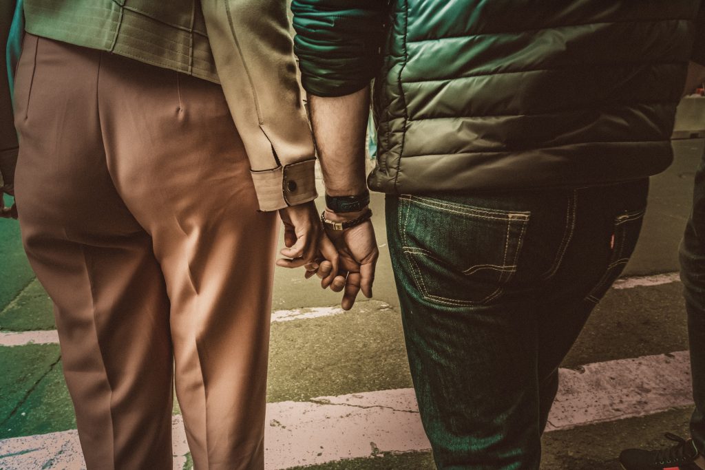 Intertwined fingers, a couple holding hands.