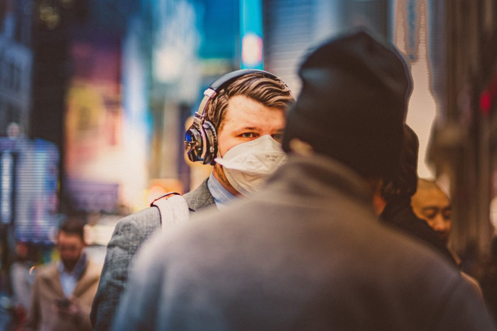 A business man walks down the street wearing a mask, Photo by Petar Pavlov. 