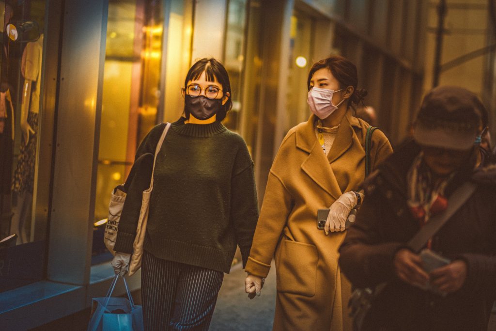 Two women walk down the street wearing masks, Photo by Petar Pavlov. 