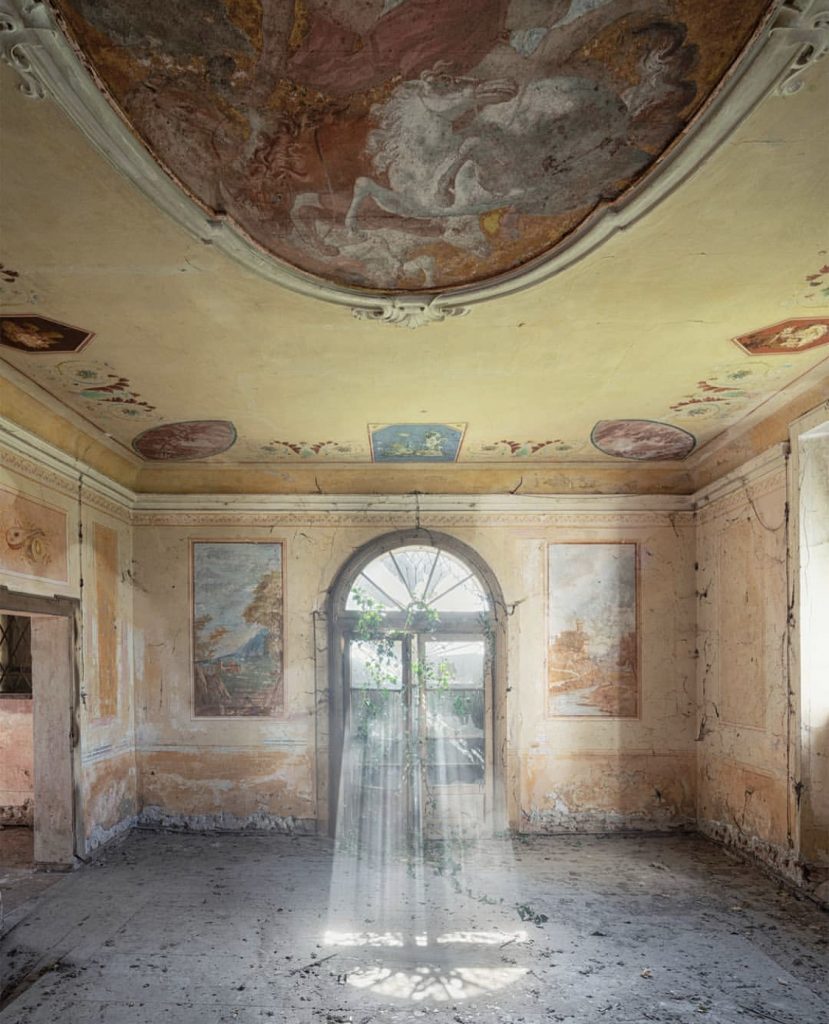 Arcana Imperii by Nicola Bertellotti. Light floods an abandoned room with sand colored walls.