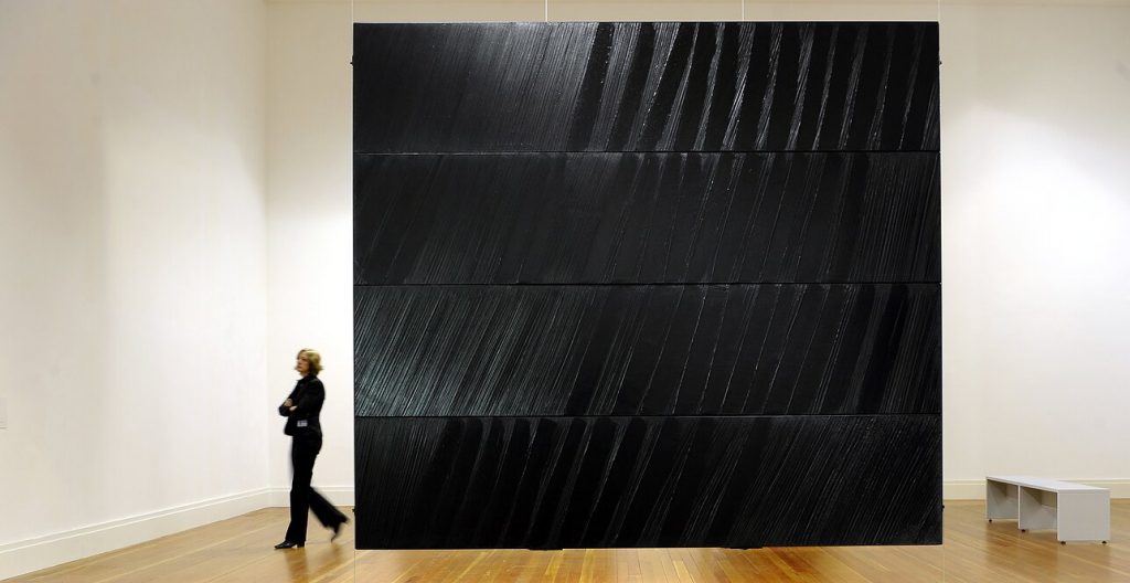 A woman walks past Pierre Soulages work in a gallery