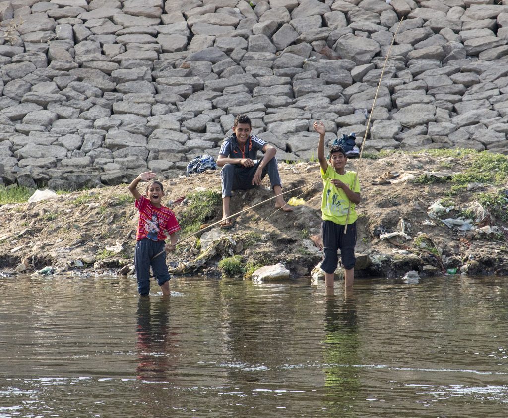 Childrenn fishing and waving on the Nile. 