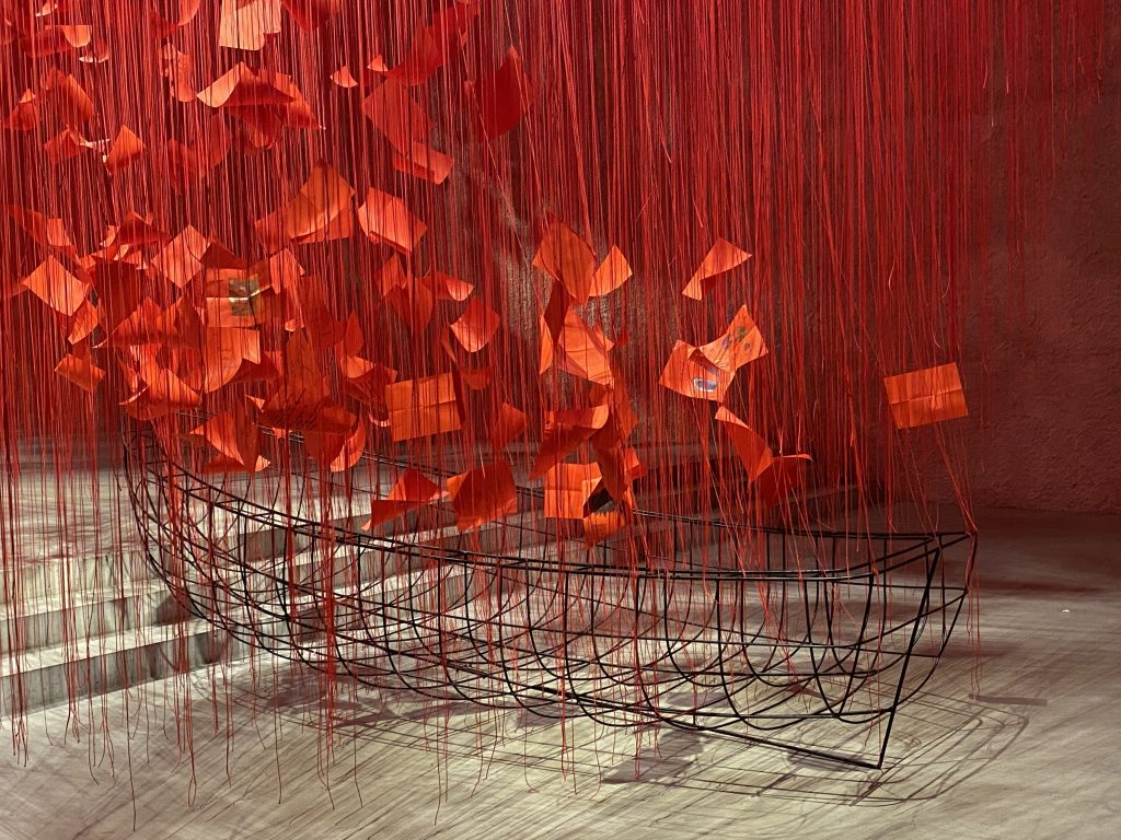 Red threads engulf the boat at Chiharu Shiota's exhibition at Koenig Galerie (KÖNIG GALERIE) in Berlin.  